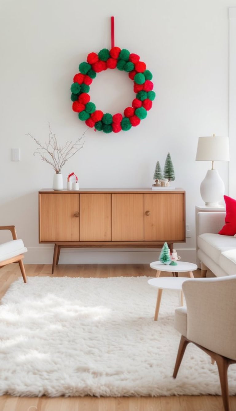 A living room decorated for the holidays, featuring a large red and green pom-pom wreath on the wall, a wooden sideboard with small Christmas tree decorations, a vase with branches, modern white and wooden furniture, and a fluffy white rug.